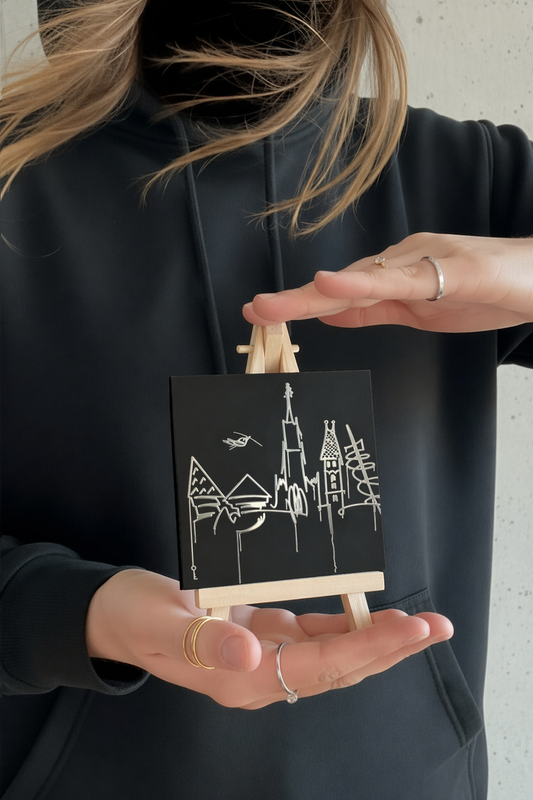 Person hält einen 10 × 10 cm großen Designspiegel Mini mit spiegelndem Motiv Donauufer