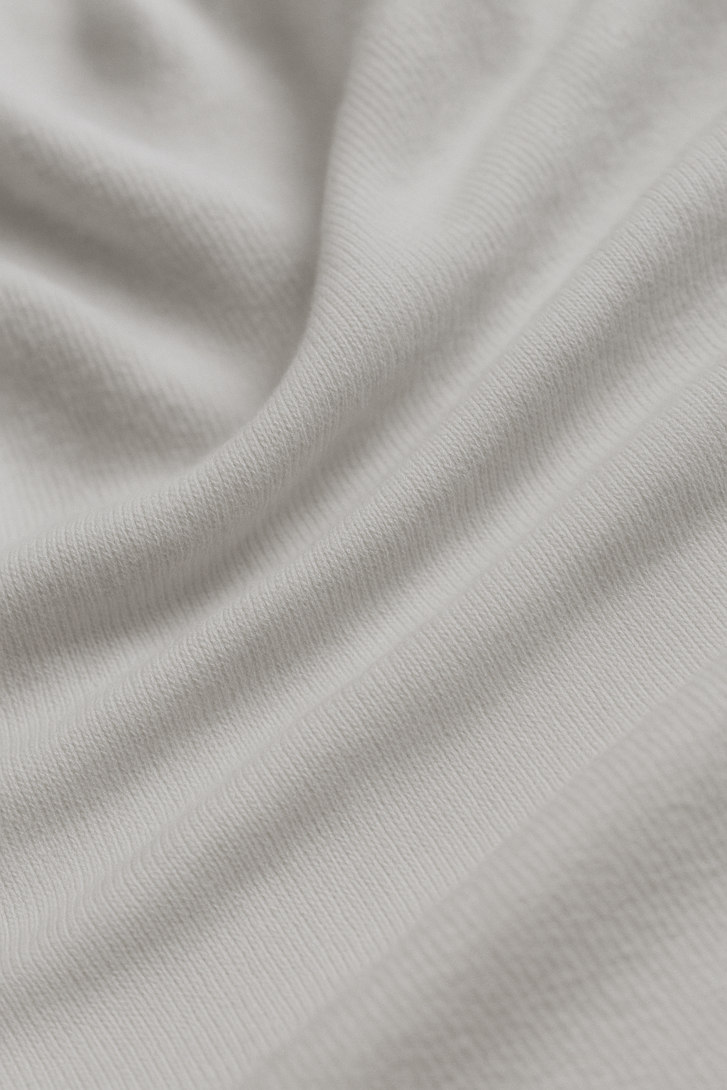 "Nahaufnahme der feinen Baumwollstruktur eines weißen T-Shirts – nachhaltige Bio-Baumwolle mit weichem Faltenwurf, minimalistisches Streetwear-Design von I WAS HERE."