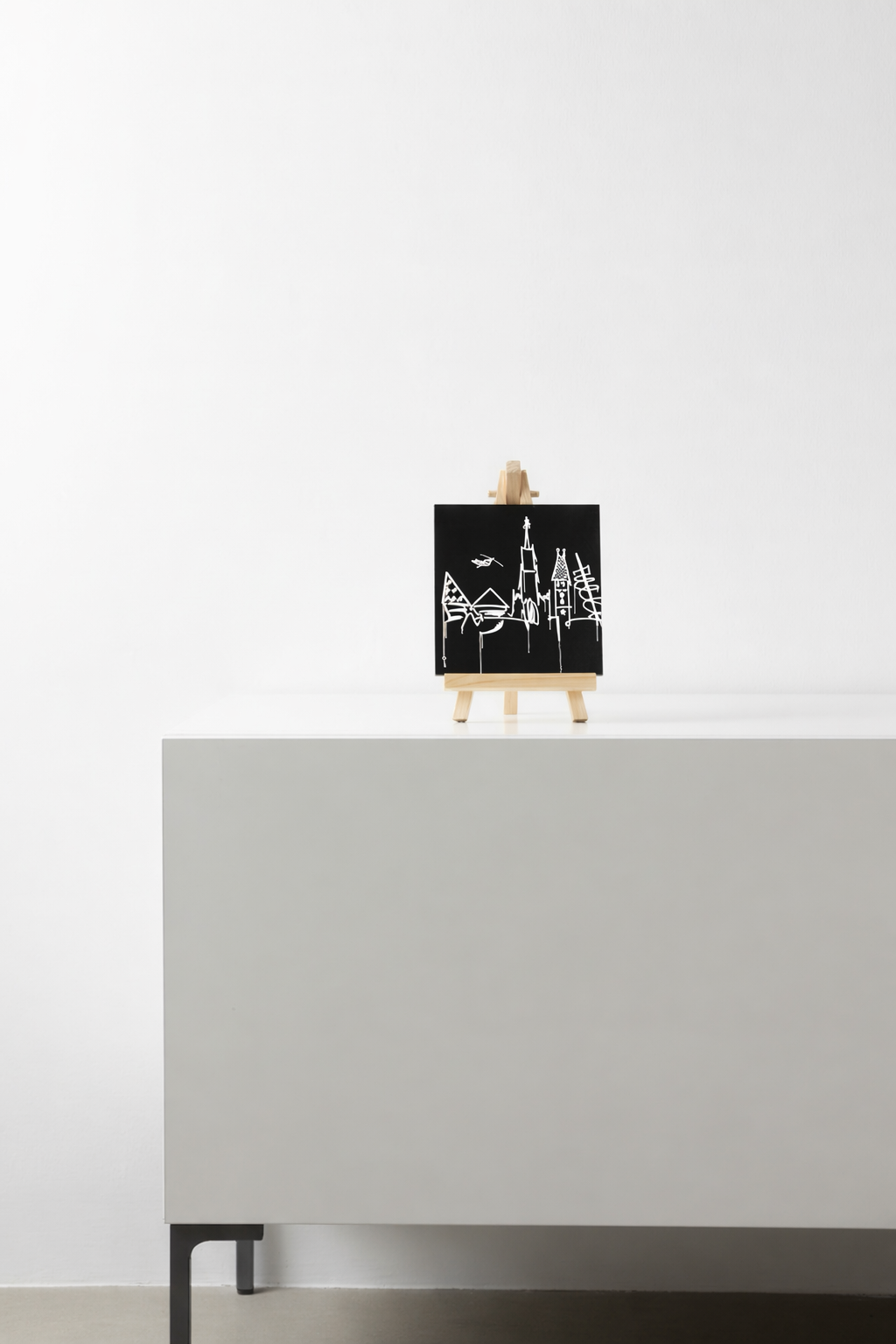 Schwarzer Designspiegel Mini mit Motiv Donauufer als Dekoration auf einem Sideboard
