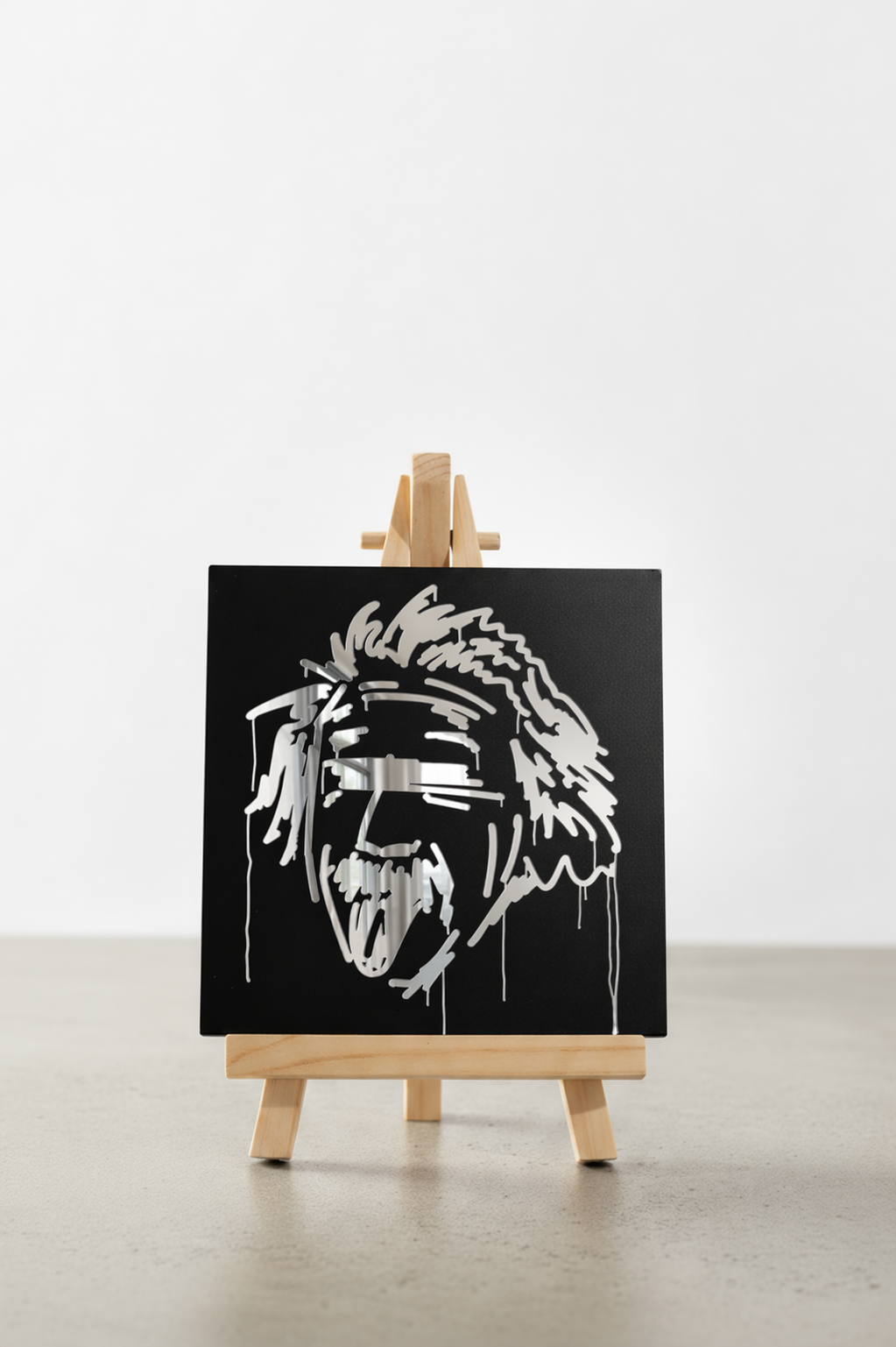 Schwarzer Designspiegel Mini in 10 × 10 cm mit spiegelndem Motiv Albert Einstein auf einer Holzstaffelei
