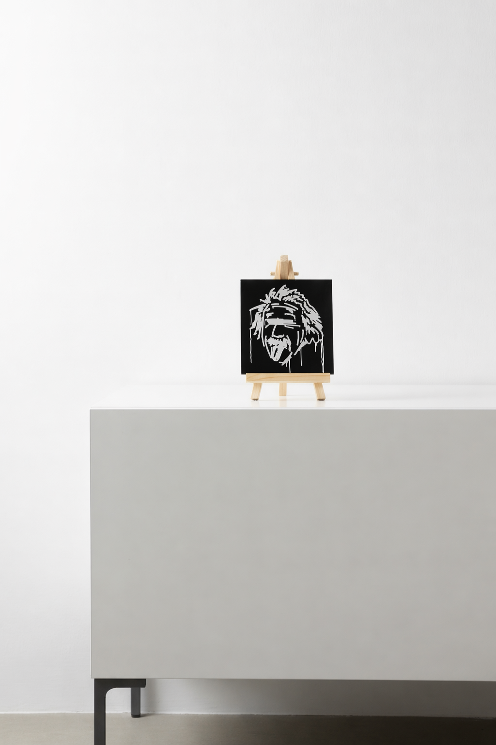 Schwarzer Designspiegel Mini mit Motiv Albert Einstein als Dekoration auf einem Sideboard
