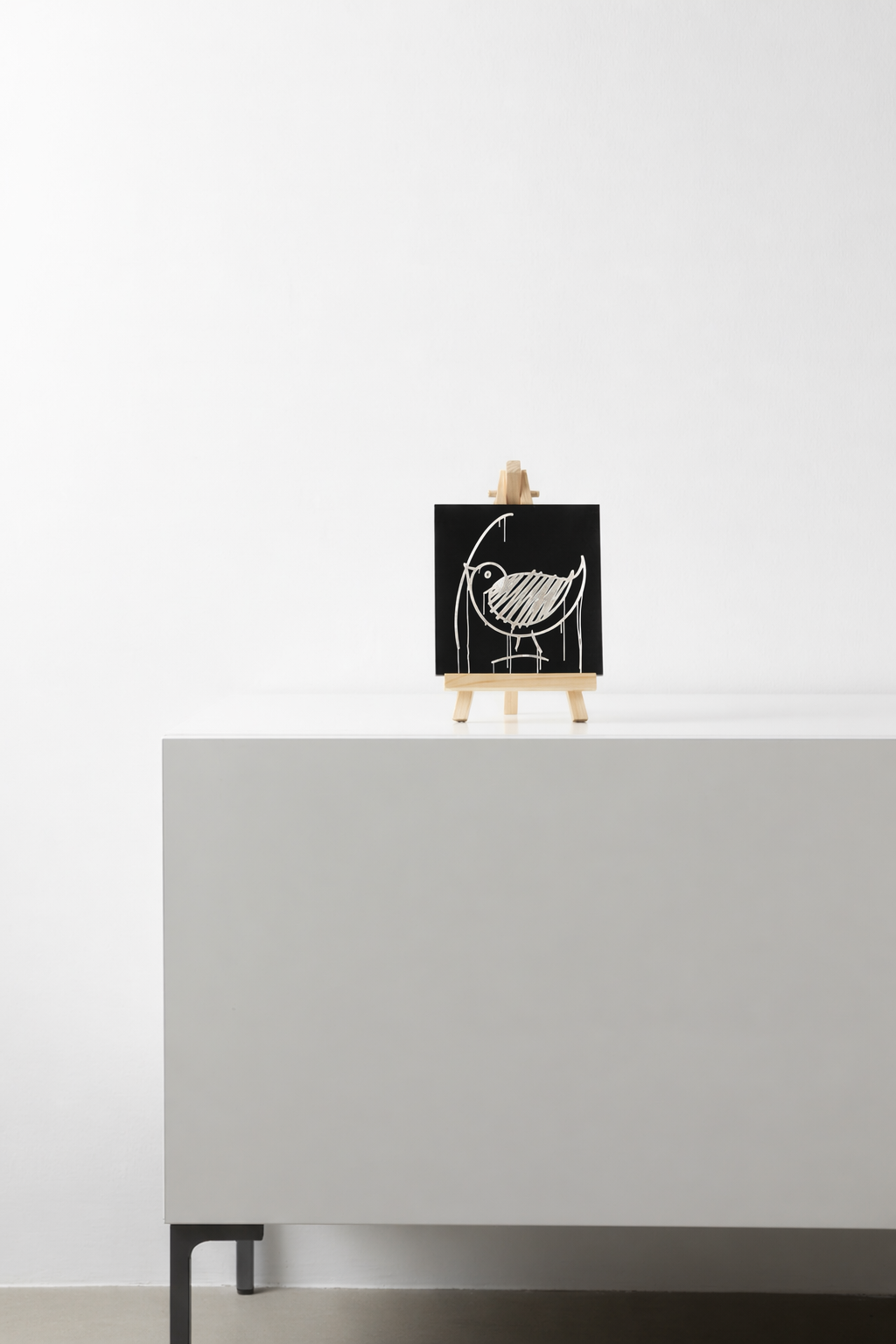 Schwarzer Designspiegel Mini mit Motiv Ulmer Spatz als Dekoration auf einem Sideboard
