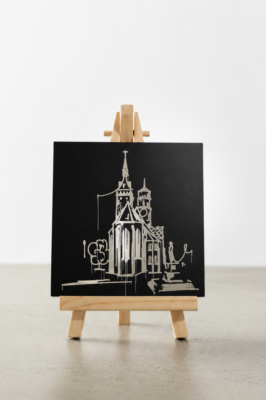 Schwarzer Designspiegel Mini mit spiegelndem Motiv Stiftskirche in Stuttgart auf einer Holzstaffelei