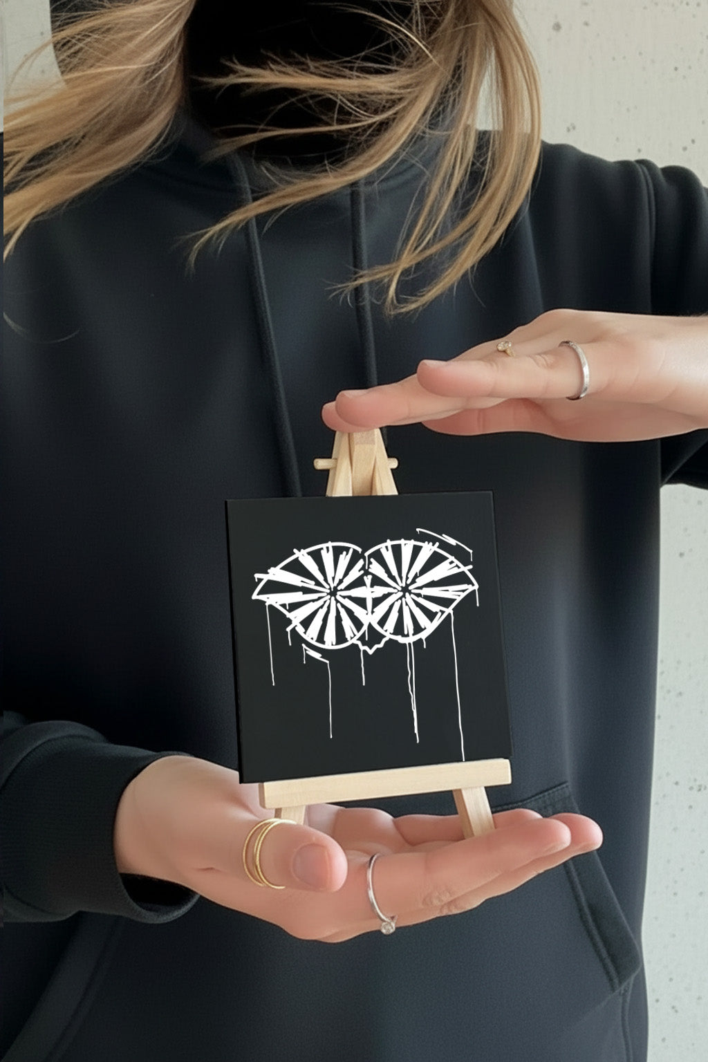 Designspiegel Mini Schneider von Ulm im schwarz-weißen Urban-Art-Stil, in zwei Händen gehalten für Größenvergleich – modernes Deko- und Geschenkprodukt