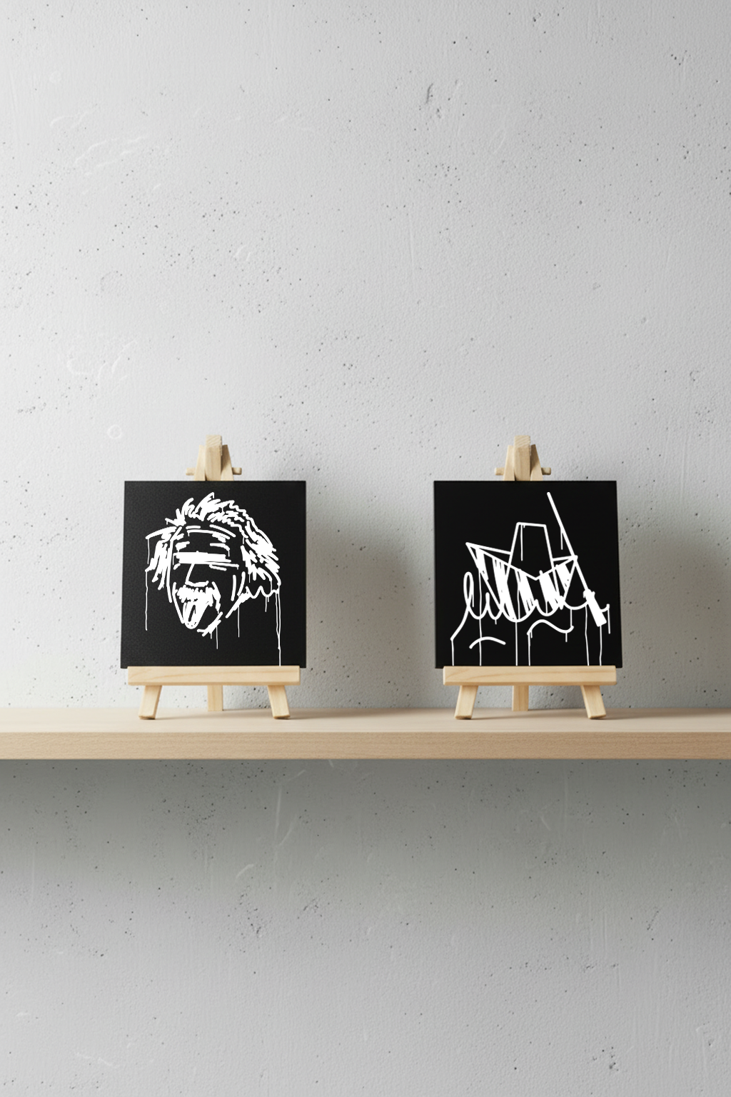 Zwei Designspiegel Mini – Ulmer Schachtel und Einstein Motiv – nebeneinander auf Regal mit Staffeleien.