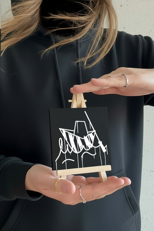 Designspiegel Mini Ulmer Schachtel – kleine schwarze Spiegelplatte mit weißem Ulm-Motiv, von einer Person in der Hand gehalten.