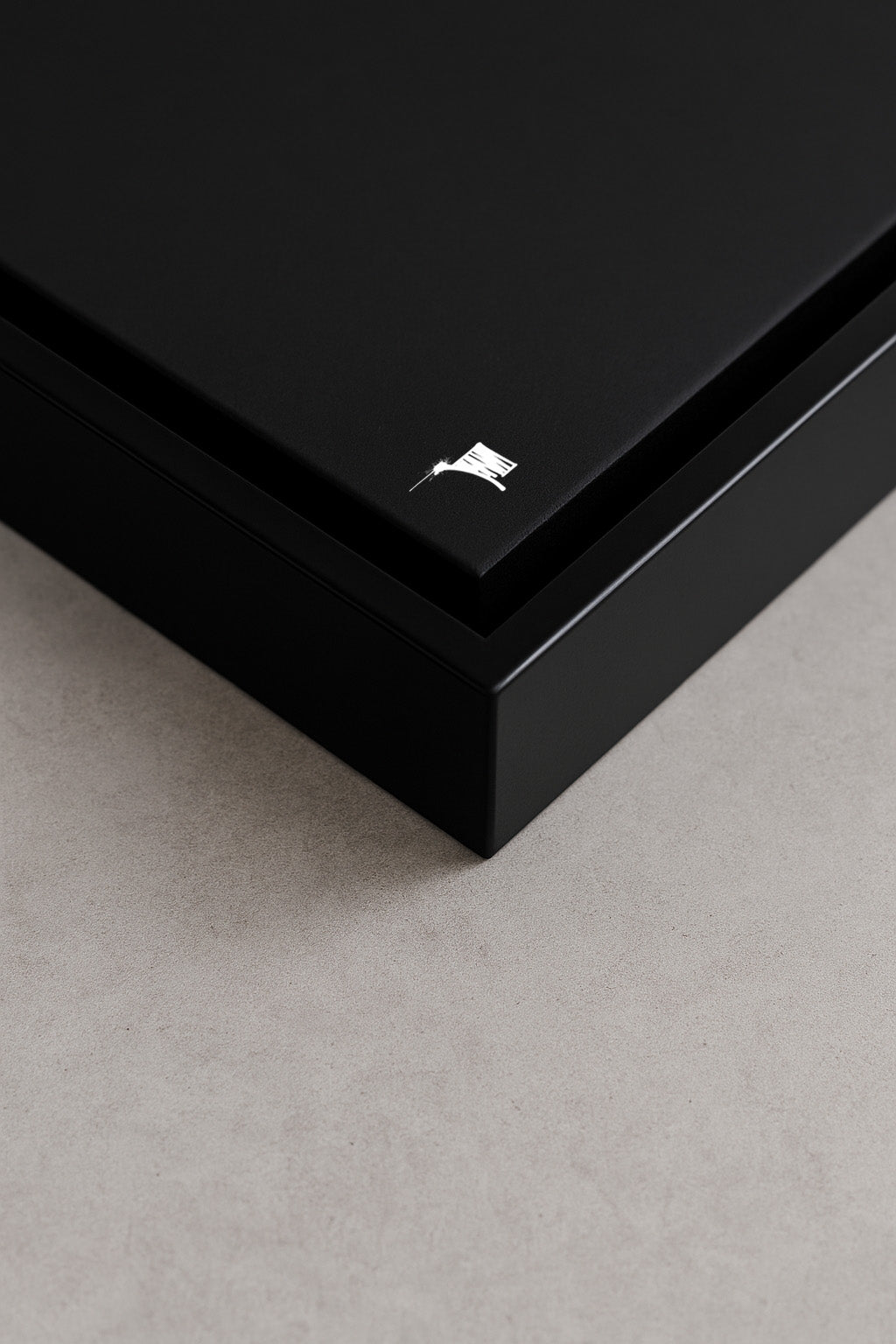 Detailaufnahme eines matt schwarzen Designspiegels im hochwertigen Schattenfugenrahmen auf hellem Betonuntergrund, minimalistisches Urban-Art-Branding