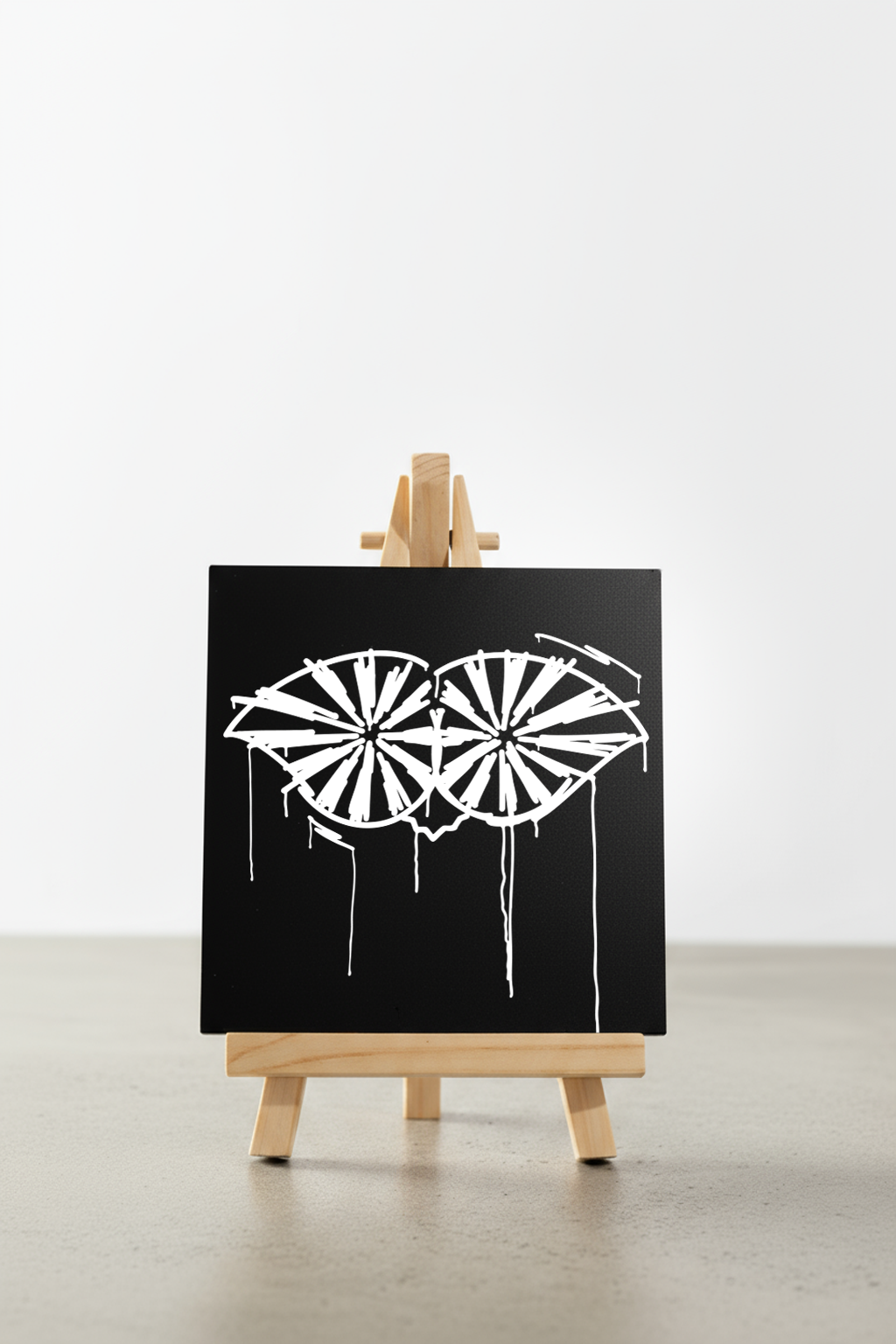 Designspiegel Mini Schneider von Ulm in Schwarz mit weißem Urban-Art-Motiv auf kleiner Staffelei, frontal fotografiert – moderne Deko und Geschenkidee