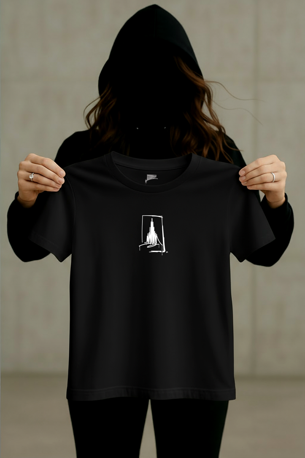 Schwarzes Urban-Art T-Shirt mit weißem Münster-Line-Art-Print, von einer Person mit Hoodie vor neutralem Hintergrund gehalten.